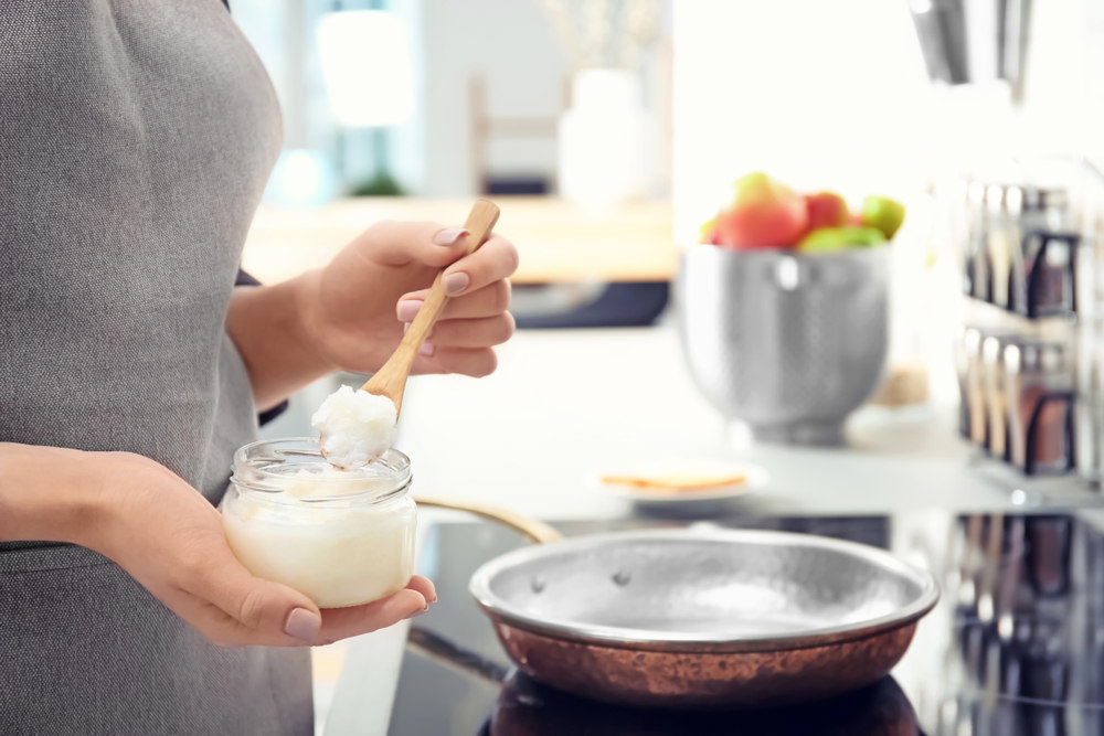 Woman,Putting,Coconut,Oil,On,Frying,Pan,In,Kitchen,,Closeup